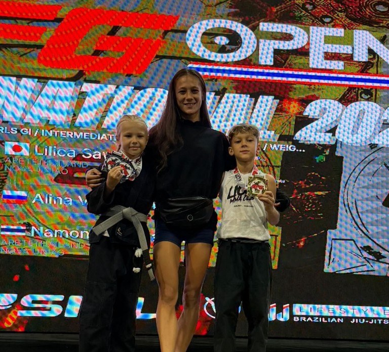 Coach Brindy with Lions Kids BJJ athletes on the AFG Open 2026 podium showing gold and silver medals